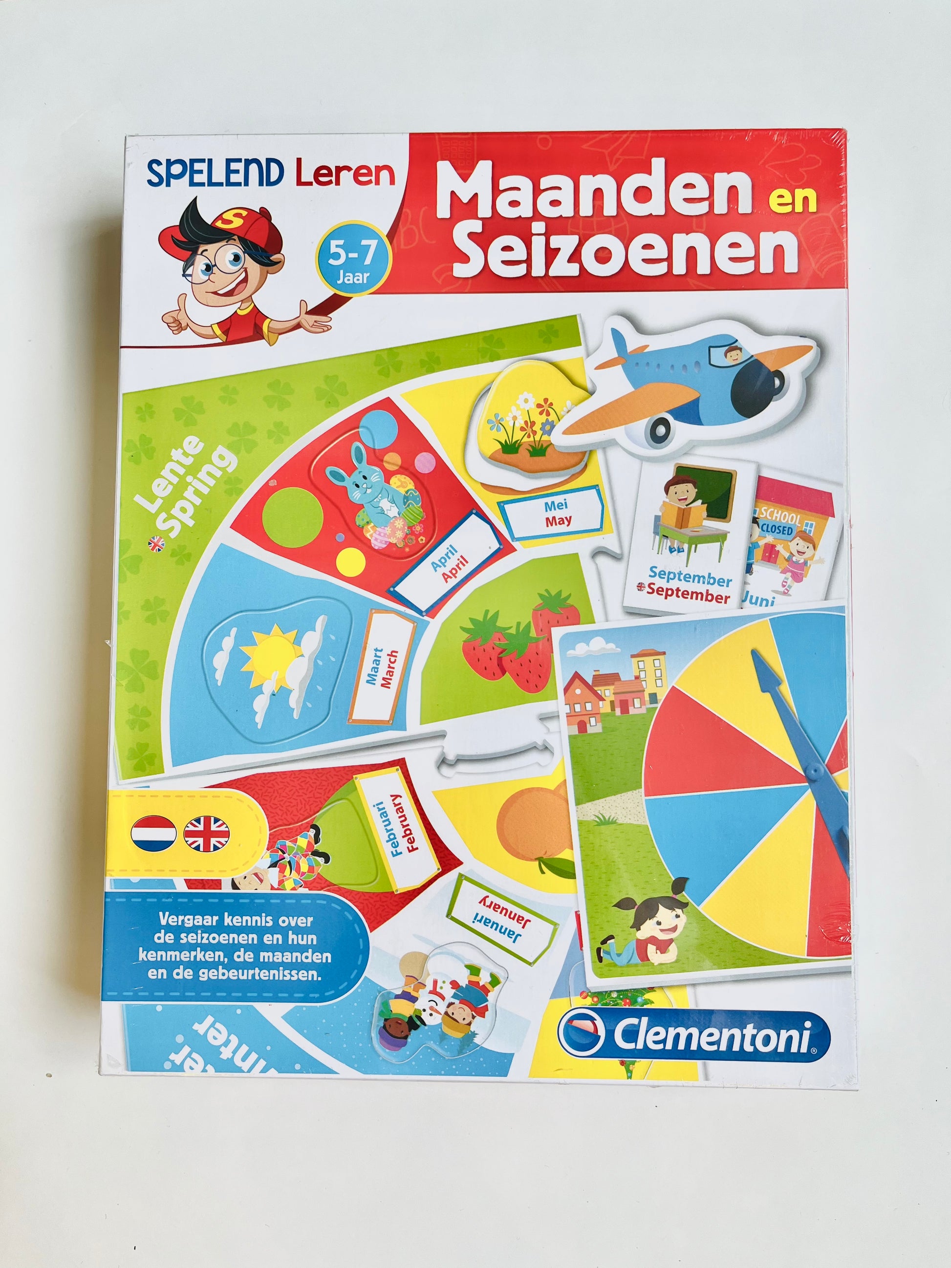 "Een groepje vrolijke kinderen speelt samen met het educatieve spel 'Spelend Leren - Maanden en Seizoenen' van Clementoni, gericht op kinderen van 5 tot 7 jaar. De kinderen leren spelenderwijs over de maanden en seizoenen, terwijl ze genieten van kleurrijke illustraties en boeiende activiteiten."