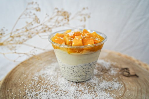 "Een kom met Vegan Biologische Chiazaad Kokos Pudding, rijkelijk bedekt met verse mango stukjes, een heerlijke tropische traktatie."